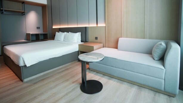 Une chambre d’hôtel moderne équipée d’un lit, d’un canapé, d’une petite table ronde et d’armoires encastrées.