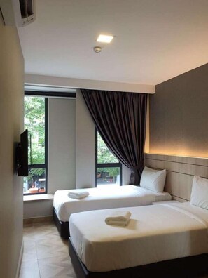 Habitación de hotel con dos camas, una televisión de pantalla plana y un amplio ventanal con cortinas.