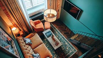 A cozy living room with a sofa, armchairs, a coffee table, and a TV mounted on the wall.