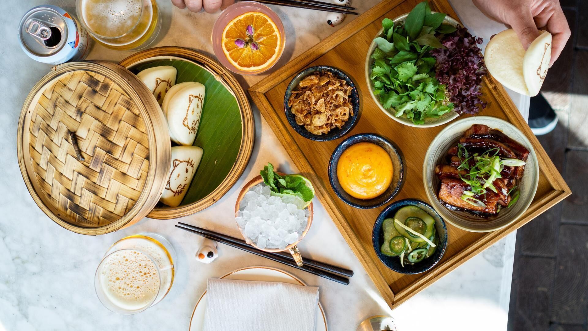 A variety of dishes including dumplings, fried items, and a bowl of greens, served on a wooden tray.