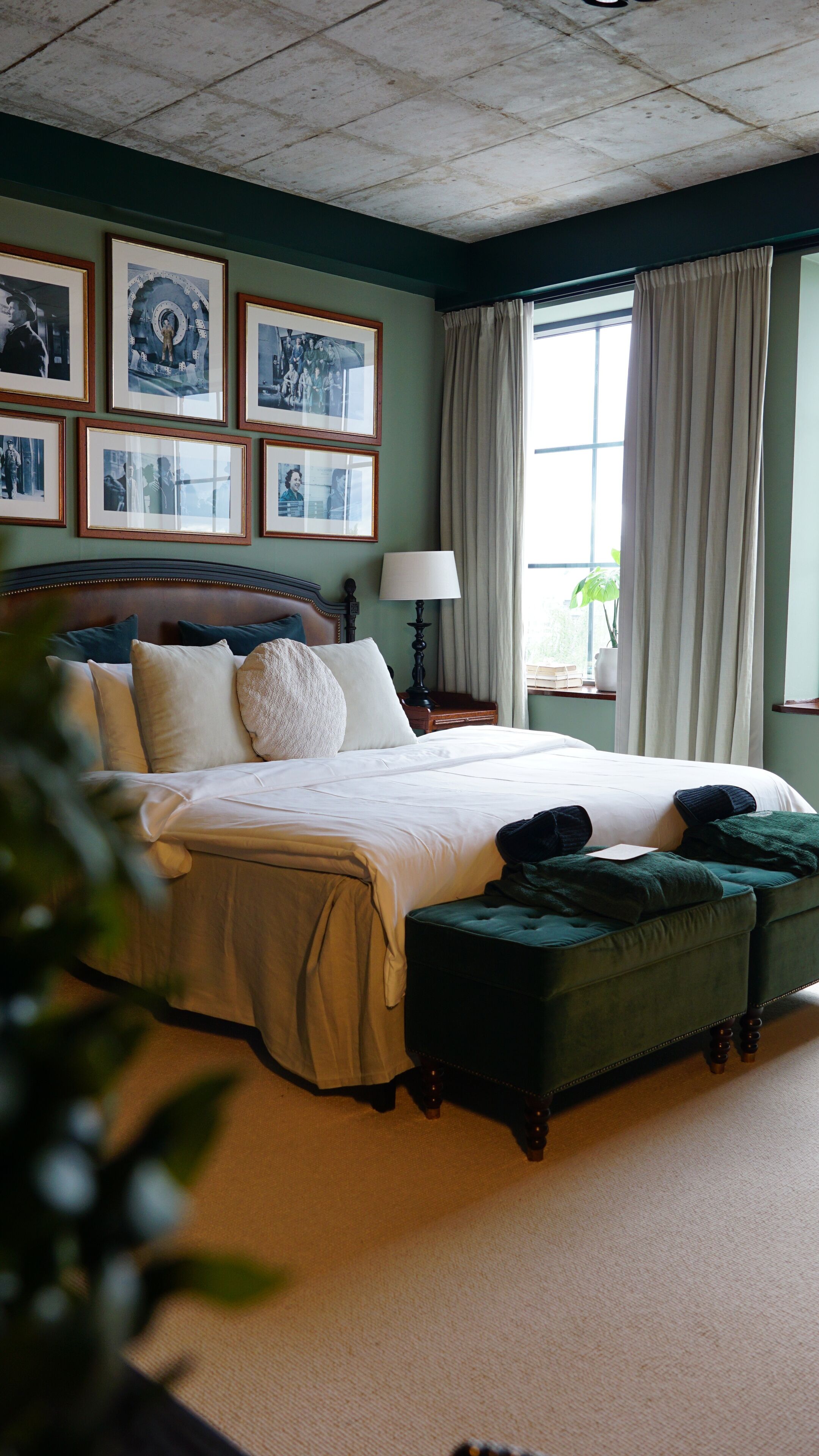 Un dormitorio ordenado con una cama grande, una mesita de noche con lámpara y una ventana con cortinas.