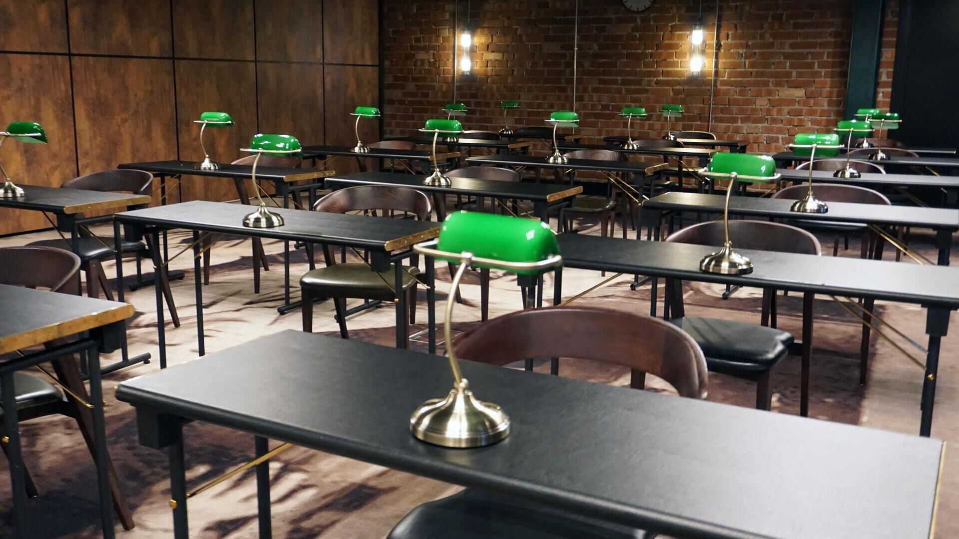 A classroom with rows of desks and chairs, each with a green lamp on top.