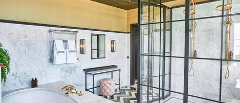 A modern bathroom with a large bathtub, a glass-enclosed shower, and a marble wall.