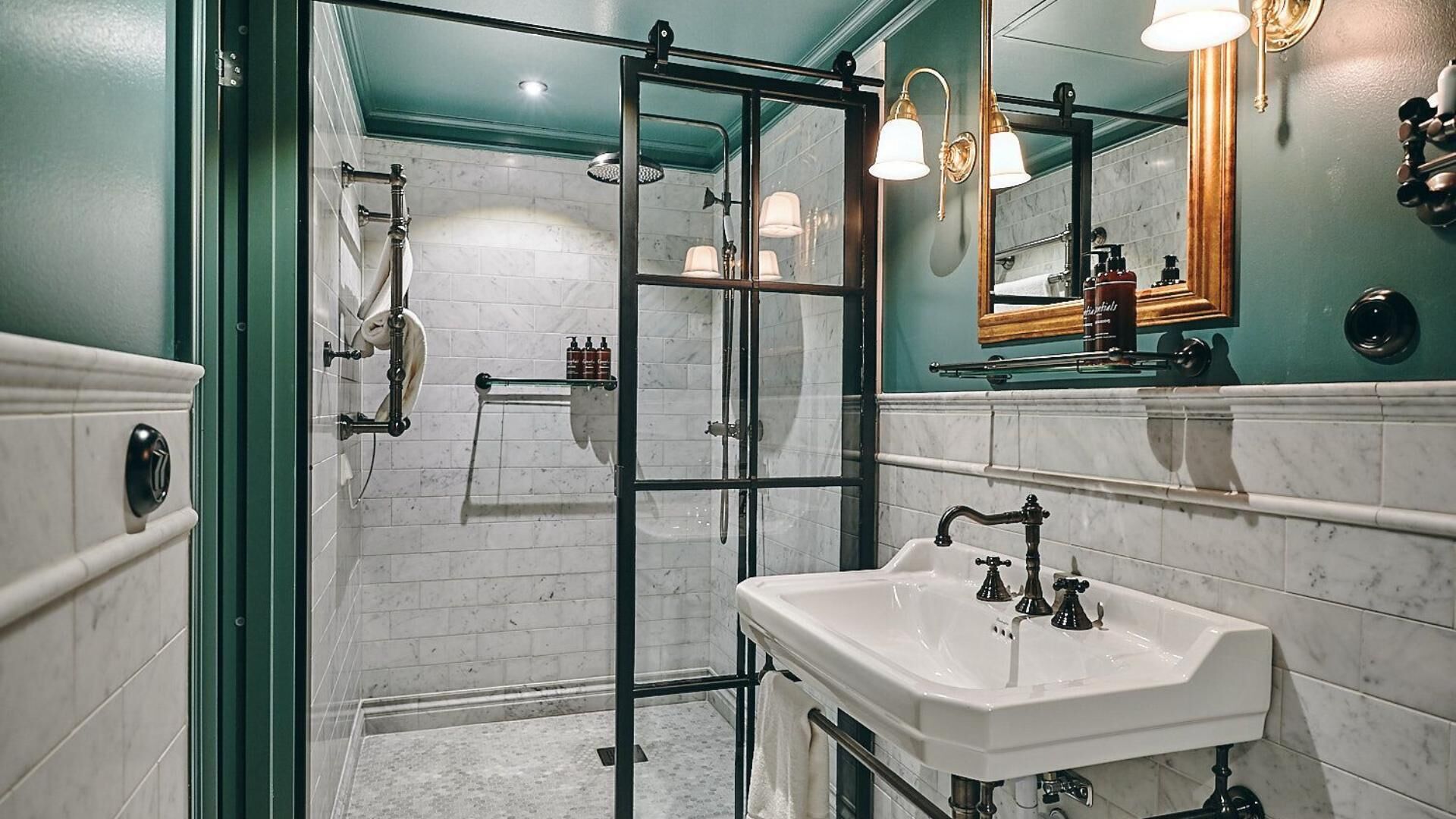 Un baño moderno con cabina de ducha de vidrio, un lavabo blanco y un espejo con marco de madera.
