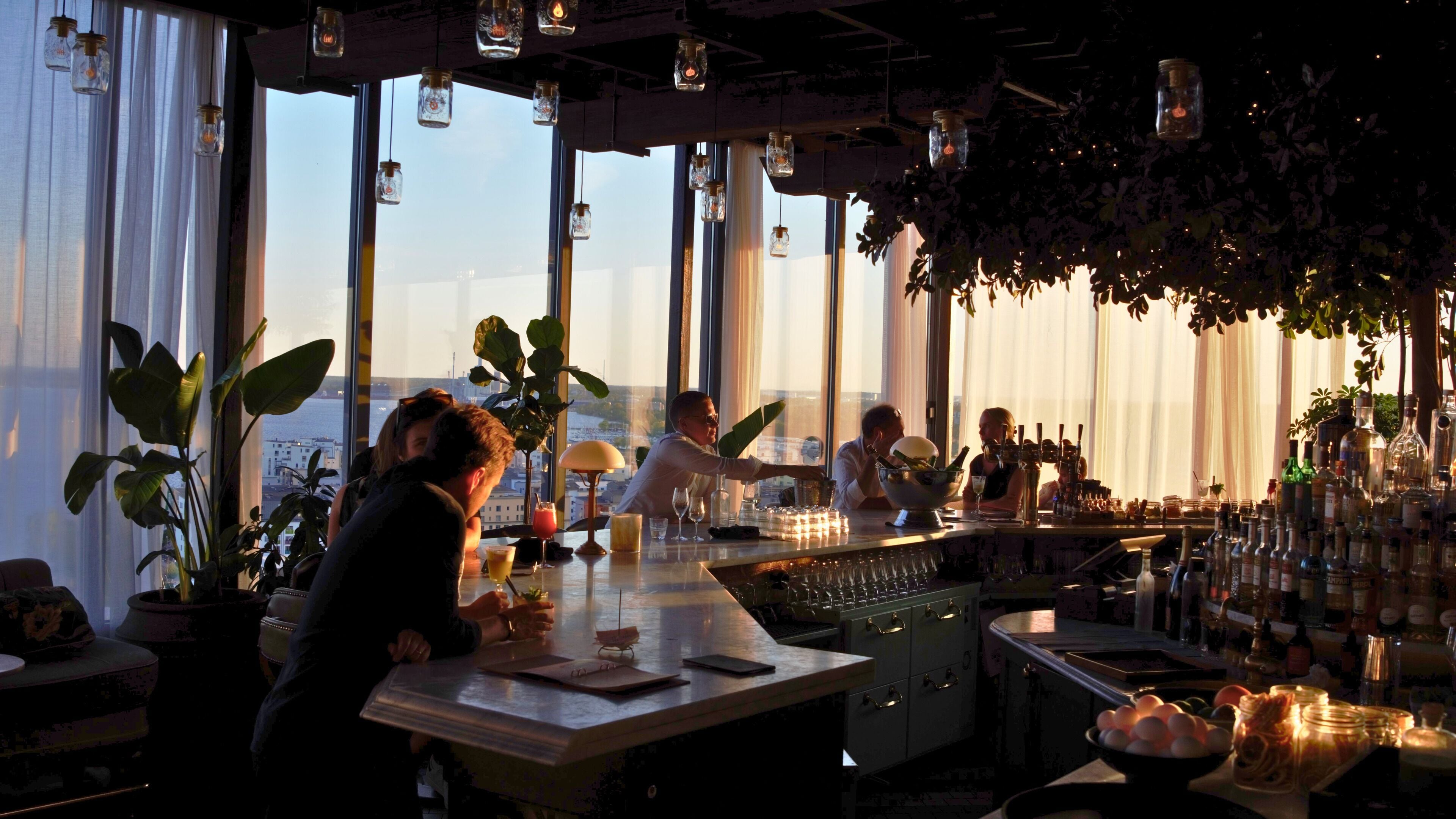 Un restaurant doté de grandes fenêtres, de luminaires suspendus et d’un espace bar.