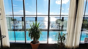 A room with large windows overlooking a marina and a pool.