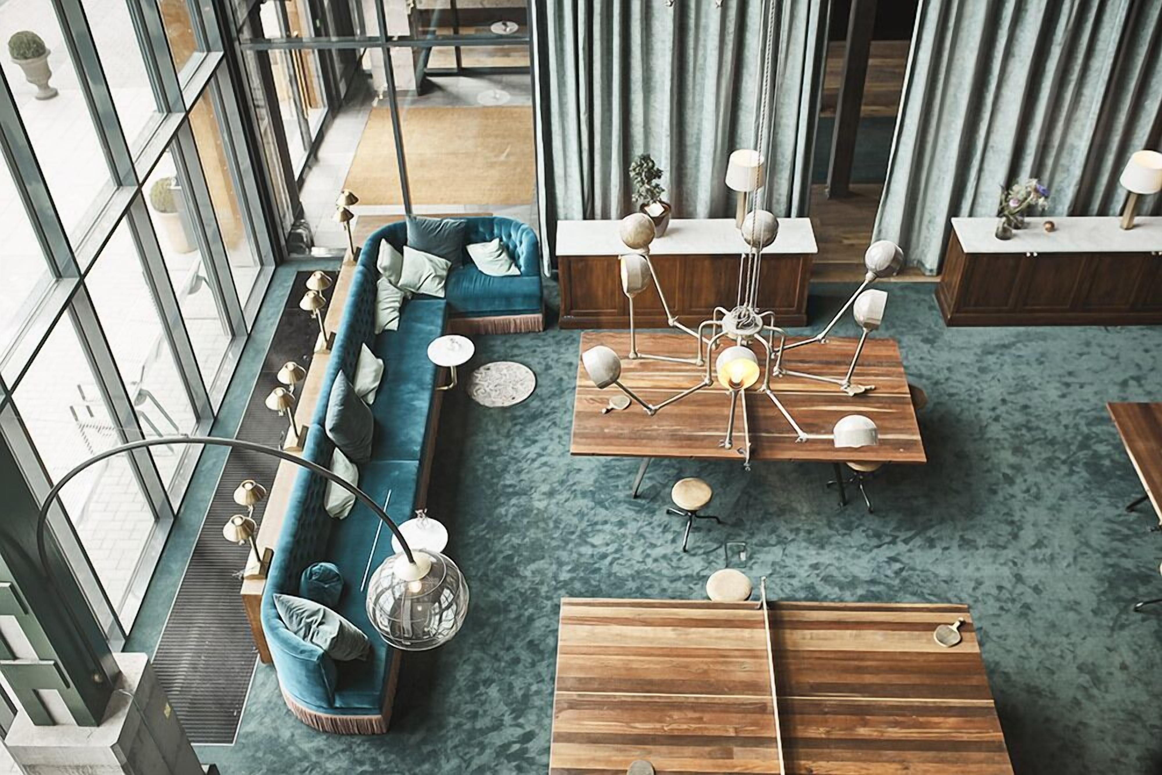 A modern interior with a blue sofa, wooden tables, and a unique chandelier.