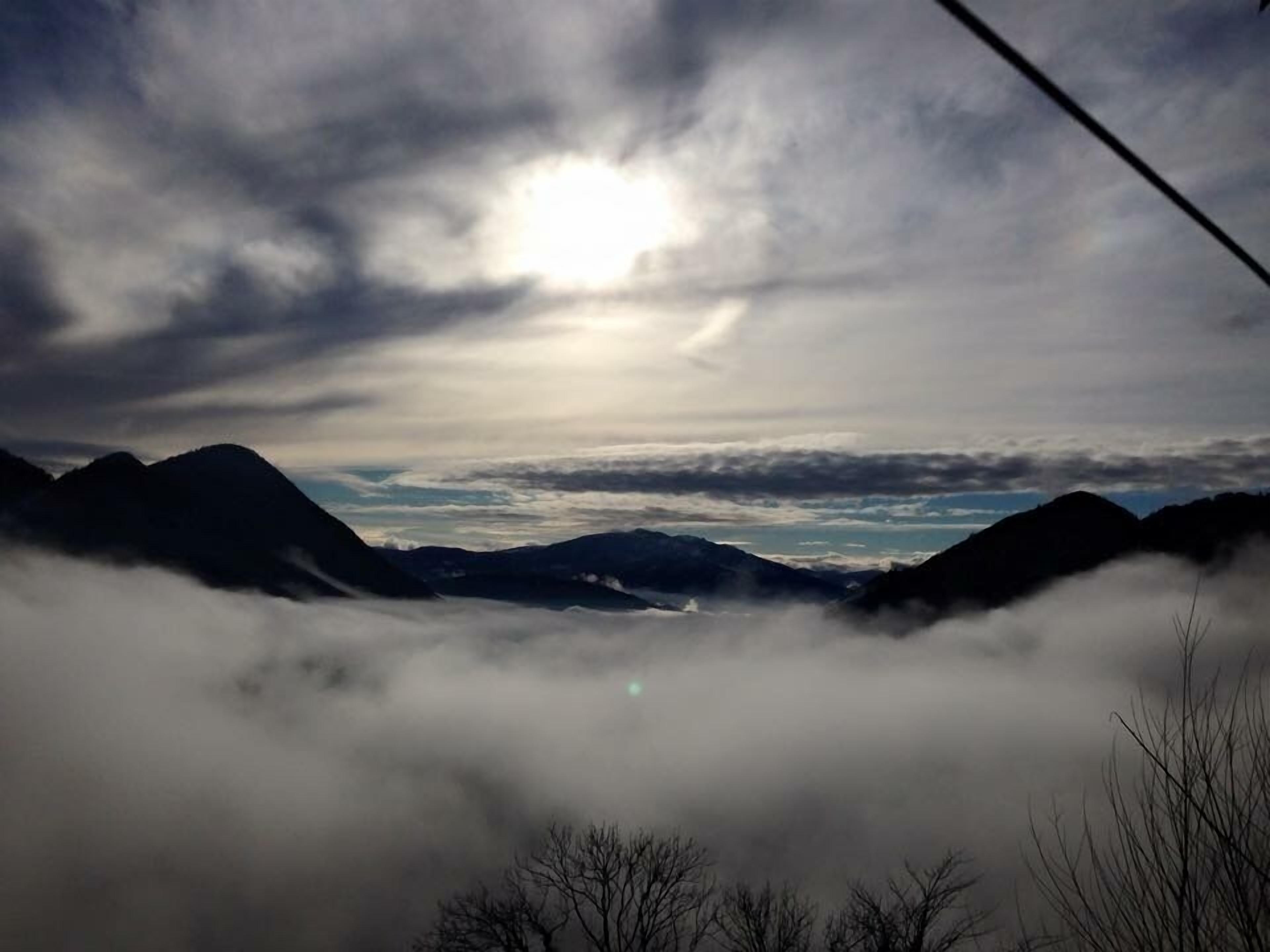 Paesaggio montuoso con cielo luminoso e nuvole.