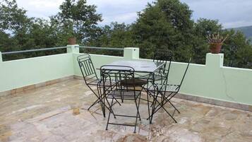 A patio with a table and chairs, surrounded by a low wall and potted plants.
