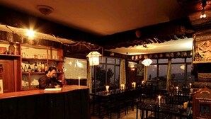 A bar area with a bartender, wooden furnishings, and a view through the windows. - Hotel New Dragon (Baluwapati Deupur)
