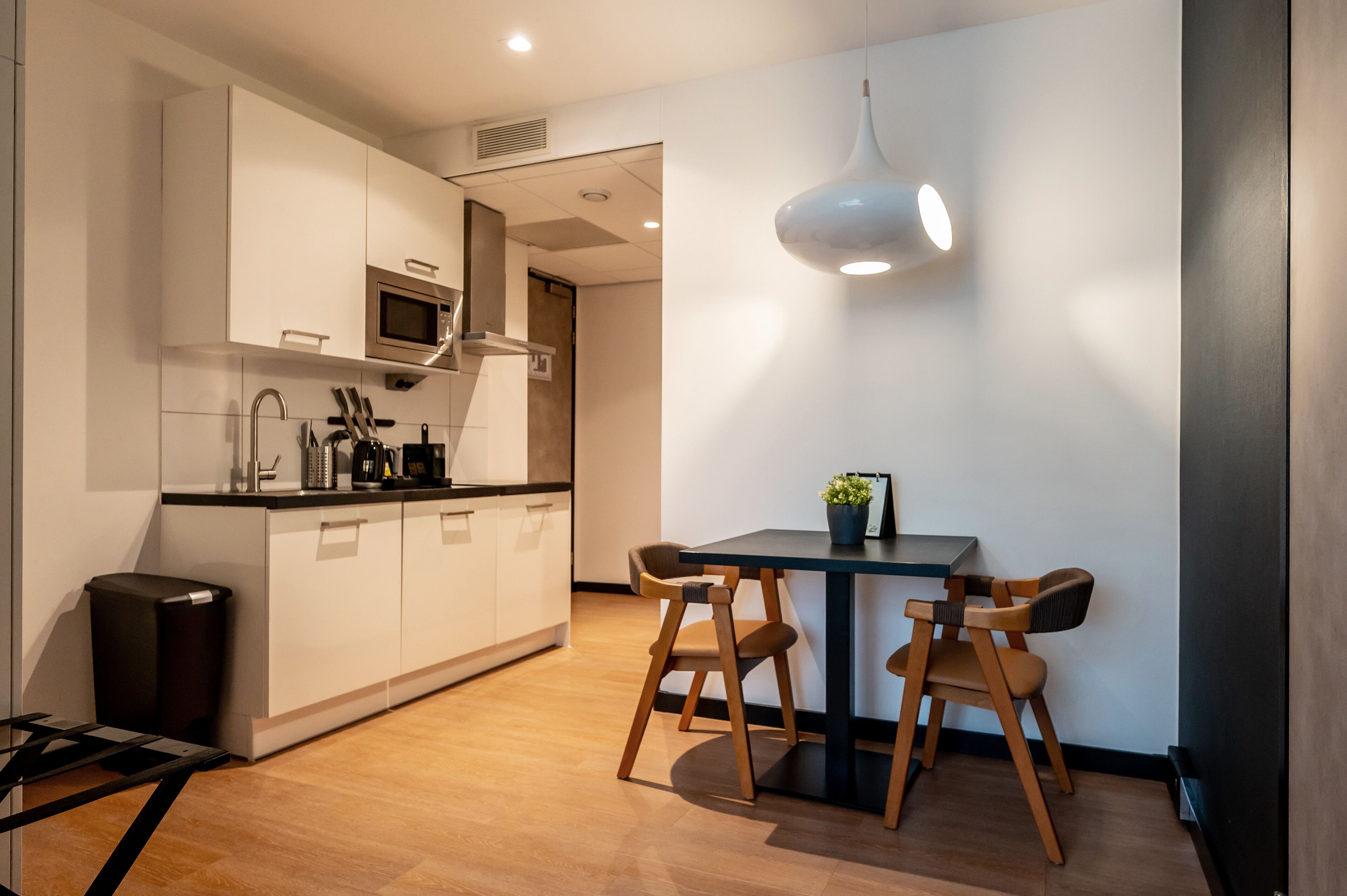 A modern kitchen with white cabinets, a microwave, and a dining area with a table and chairs.