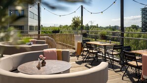 Une terrasse sur le toit, avec des sièges en plein air, des guirlandes lumineuses et une vue sur le paysage urbain.