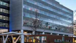 Un bâtiment moderne doté d’une façade en verre, d’une enseigne bien visible sur le dessus et d’un espace d’entrée abrité avec des sièges.