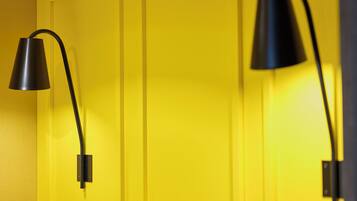Two black wall-mounted lamps against a yellow door.