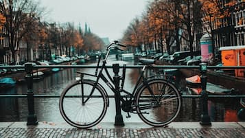 Un vélo est garé au bord d’un canal, avec un pont en arrière-plan.