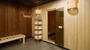 Une pièce aux finitions en bois, avec un banc, une étagère contenant des serviettes et une porte donnant sur le sauna.