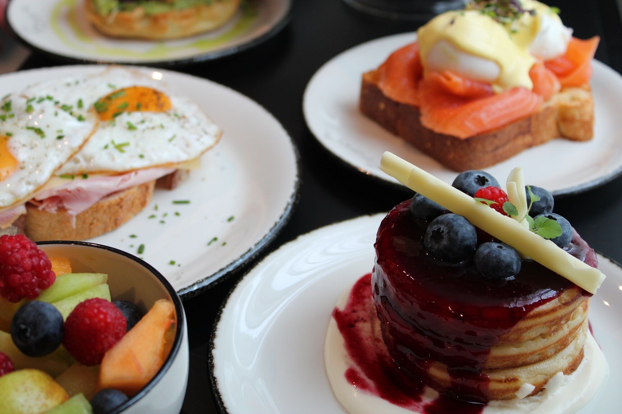 Une variété de plats pour le petit-déjeuner, présentés sur des assiettes.