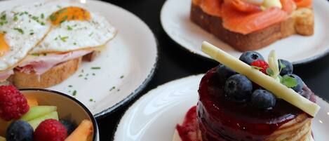 Une variété de plats pour le petit-déjeuner, présentés sur des assiettes.