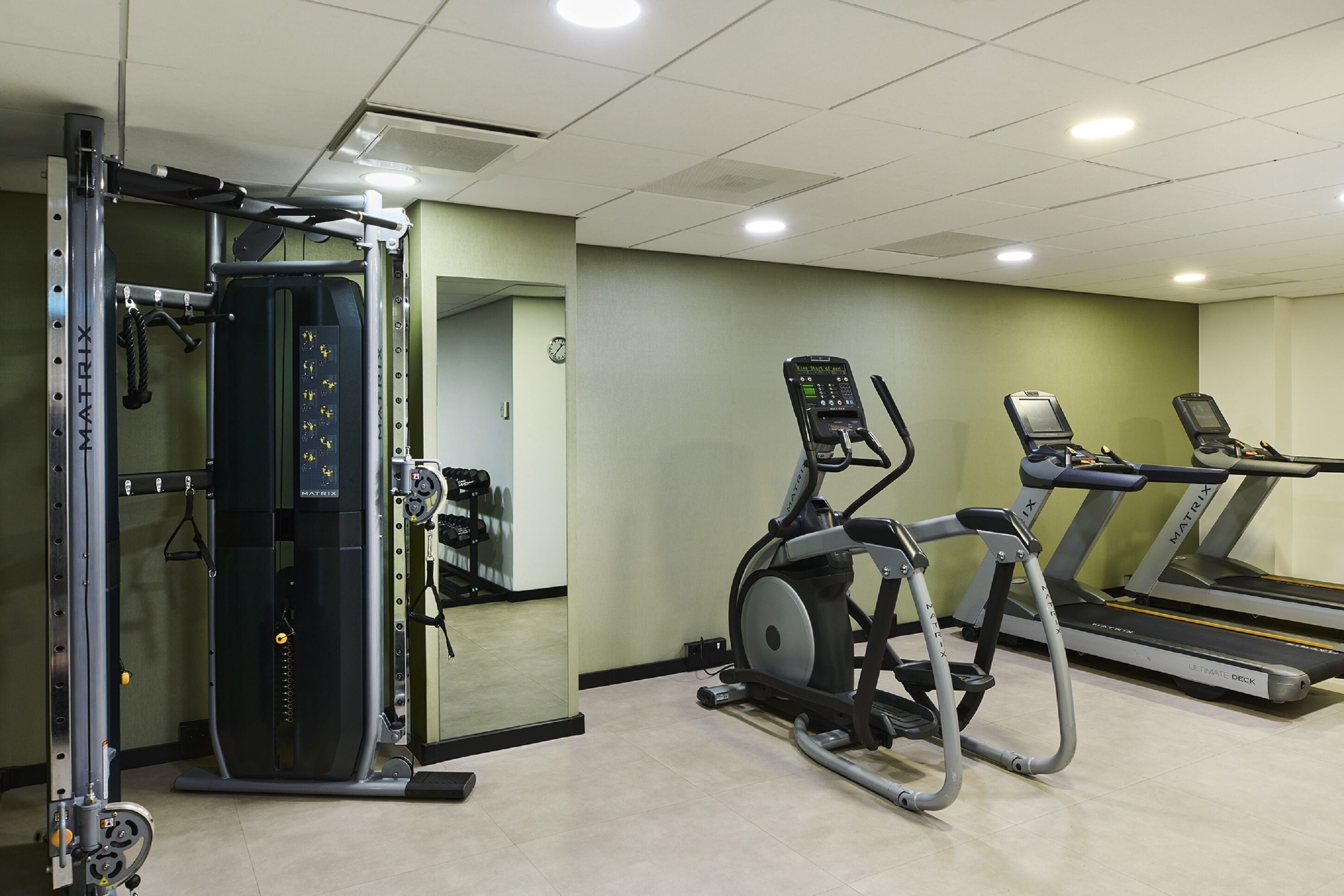 A gym with a weight machine, an elliptical, and treadmills.