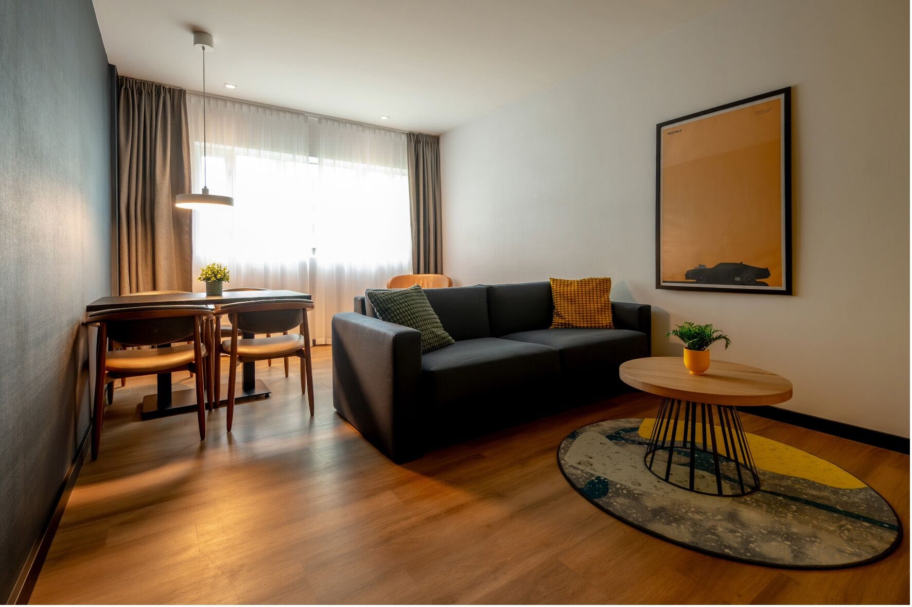 Una sala de estar moderna con un sofá, una mesa de comedor con sillas, una mesa de centro y un cuadro en la pared.