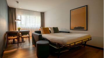 A modern hotel room with a bed, a desk, and a chair.