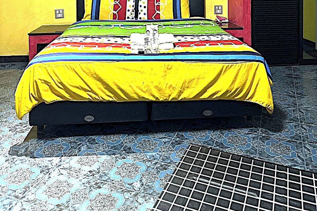 A bedroom with a bed, a nightstand, a wall-mounted artwork, and a door.