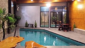 An indoor swimming pool with a wooden deck, benches, and potted plants. - Koenig Hotel Pattaya (Pattaya)