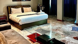 A modern hotel room with a large bed, a glass coffee table, a sofa, and a painting on the wall. - Koenig Hotel Pattaya (Pattaya)