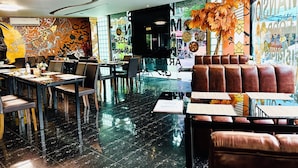 A restaurant with a modern interior, featuring a black marble floor, leather seating, and decorative wall art. - Koenig Hotel Pattaya (Pattaya)