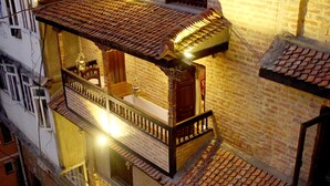 A multi-story building with a brick facade, multiple balconies, and a tiled roof. - Temple House (Lalitpur)