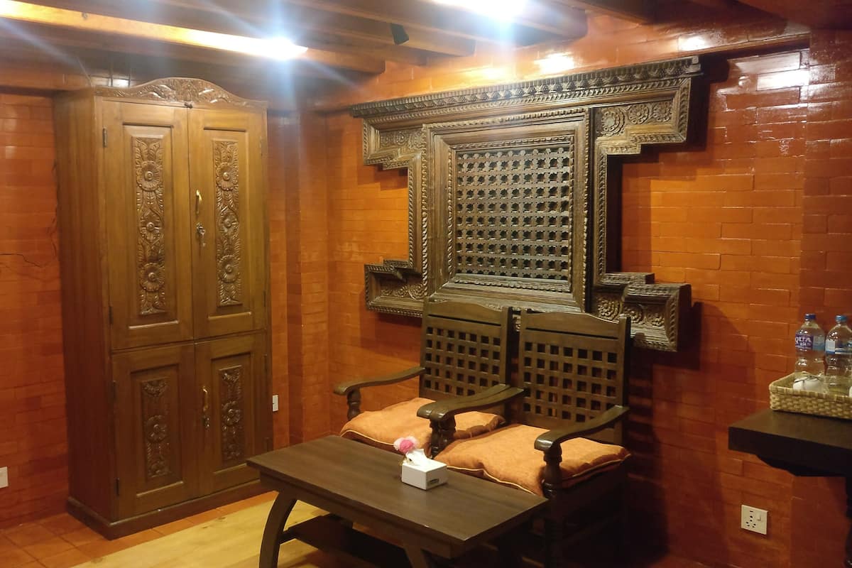 A room with a wooden wardrobe, a wooden chair with a cushion, a small table with a tissue box, and a decorative wall panel.