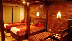 A room with two wooden beds, a wooden chair, and a brick wall with two wall-mounted lights. - Temple House (Lalitpur)