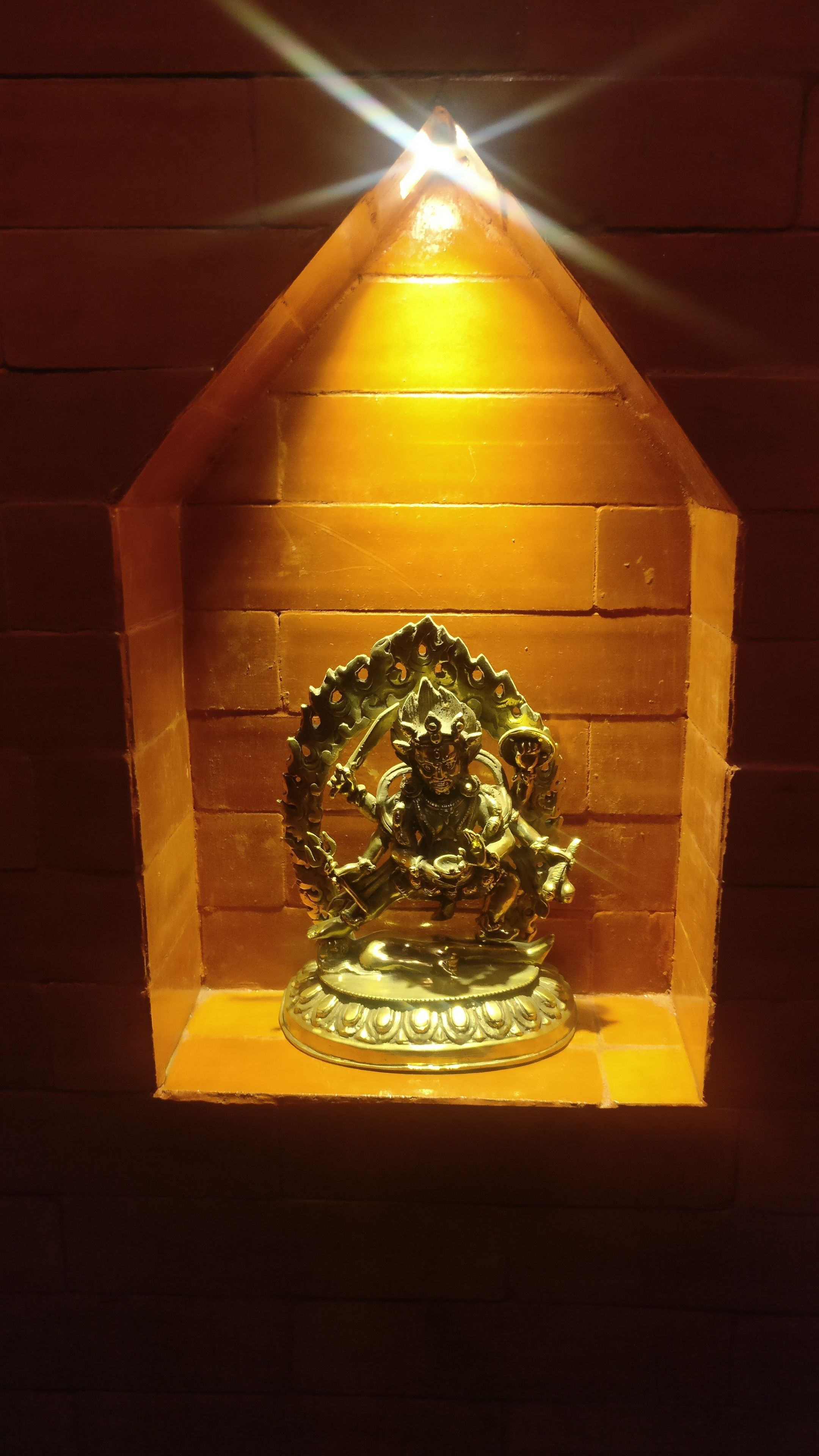 A statue of a deity in a niche with a triangular roof.