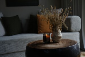 A room with a wooden table, a lit candle, and a vase with dried plants. - Viking Cottages and Apartments (Akureyri)