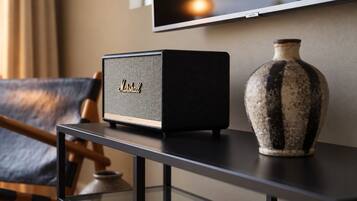 A black Marshall speaker on a black table with a vase and a chair in the background.
