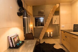 A modern kitchen with a wooden staircase, a dining table with magazines, and a black fur rug. - Viking Cottages and Apartments (Akureyri)