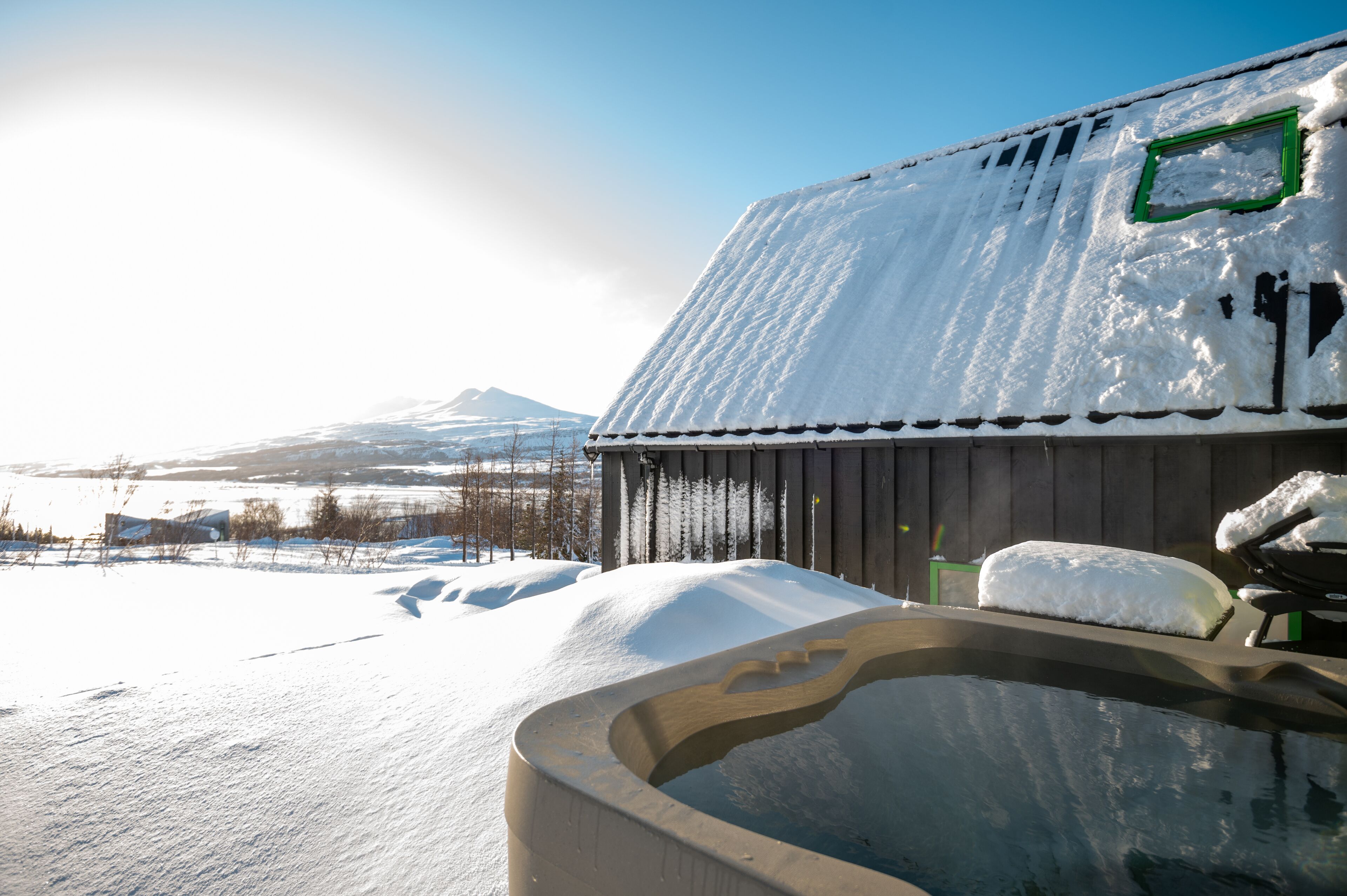A snow-covered outdoor hot tub area with a view of a mountain in the background.