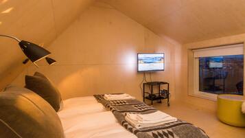 Ett modernt hotellrum med en säng, ett skrivbord, en TV och ett fönster med utsikt över staden.