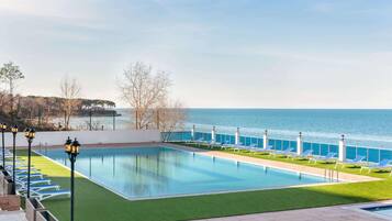 Alberca techada, alberca al aire libre y sombrillas en la alberca