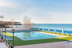 Alberca techada, alberca al aire libre y sombrillas en la alberca