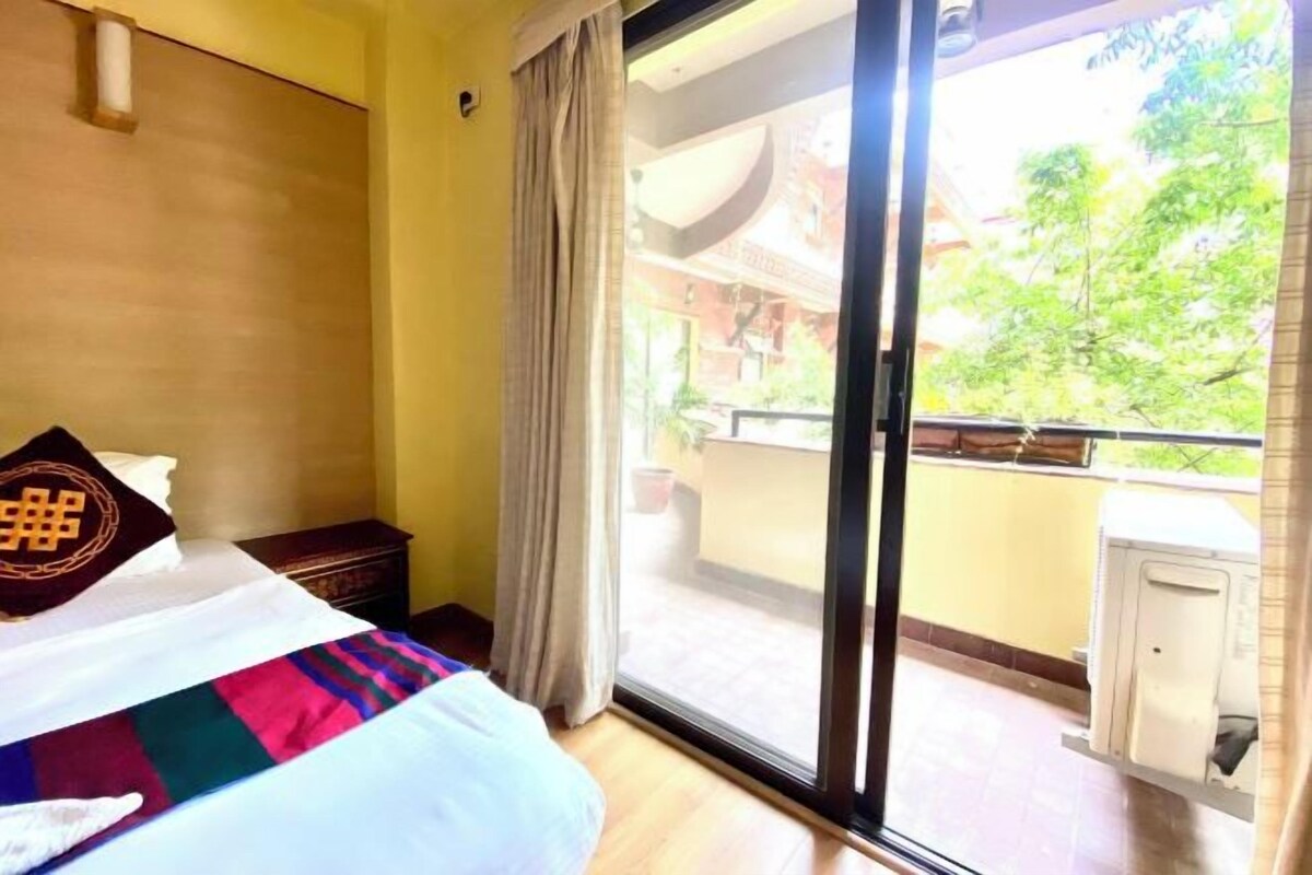 Una habitación de hotel con una cama, un ventanal y vistas a un balcón.