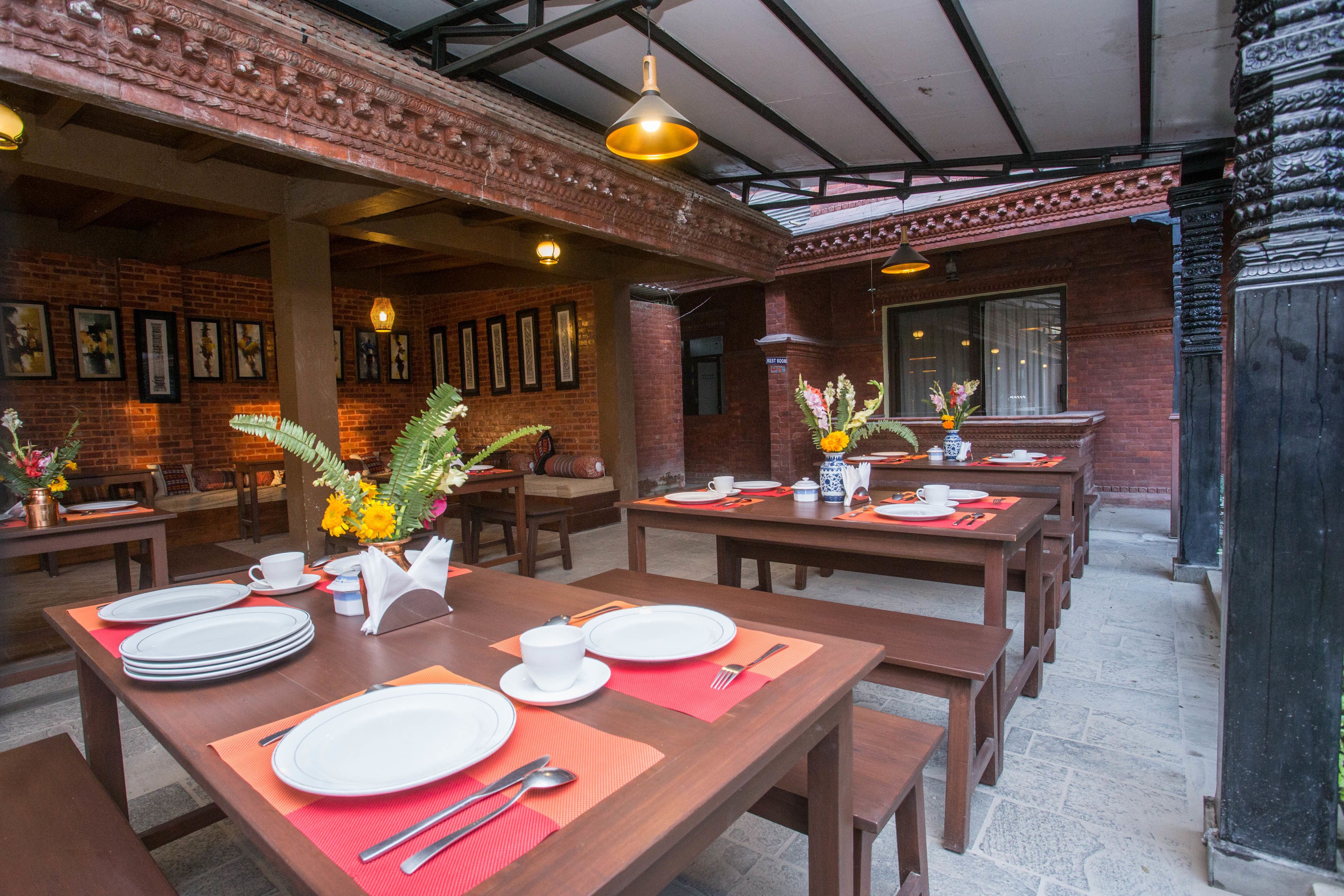 Un restaurant aux murs de briques, aux tables en bois et aux lampes suspendues.