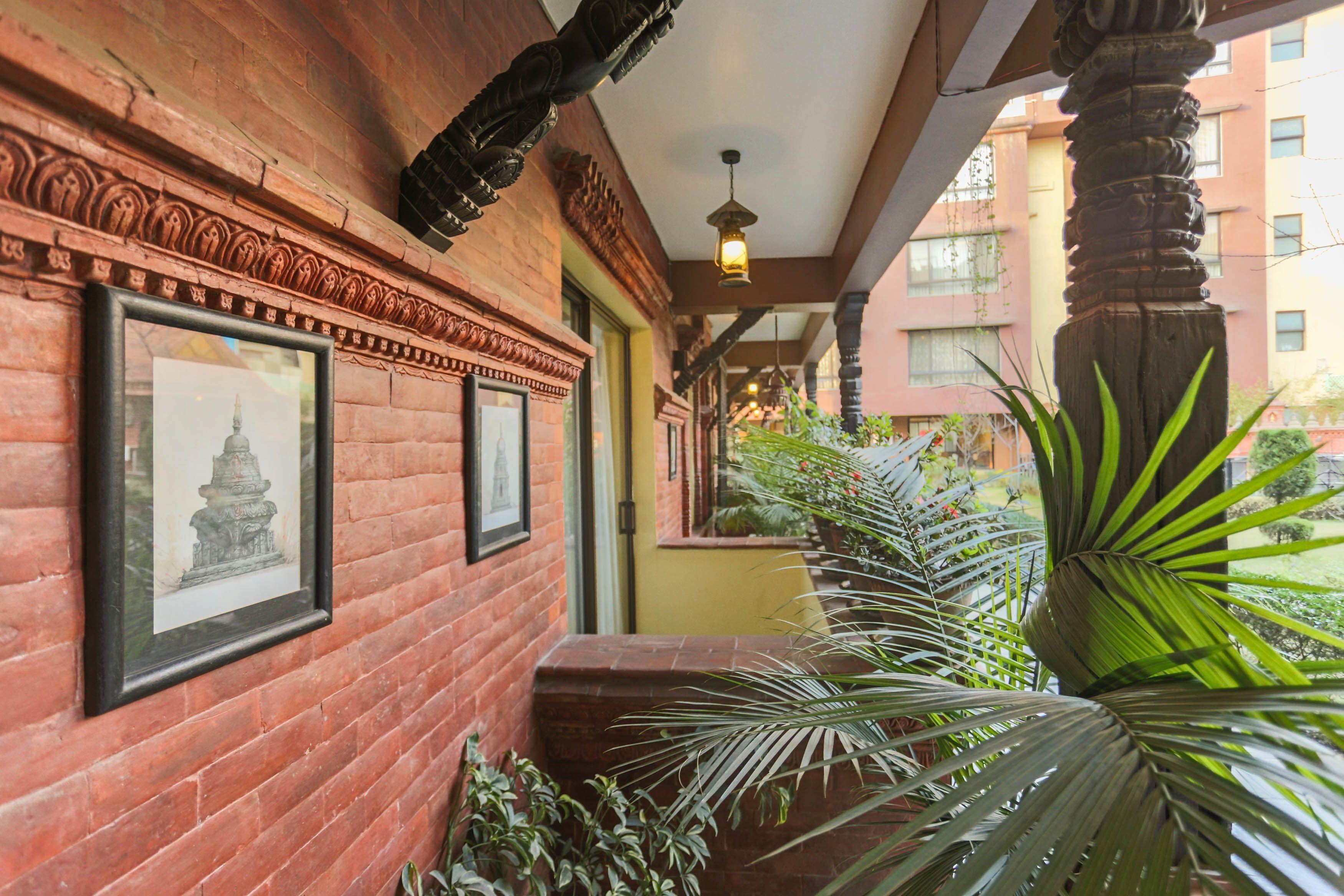A corridor with brick walls, framed pictures, and a potted plant.