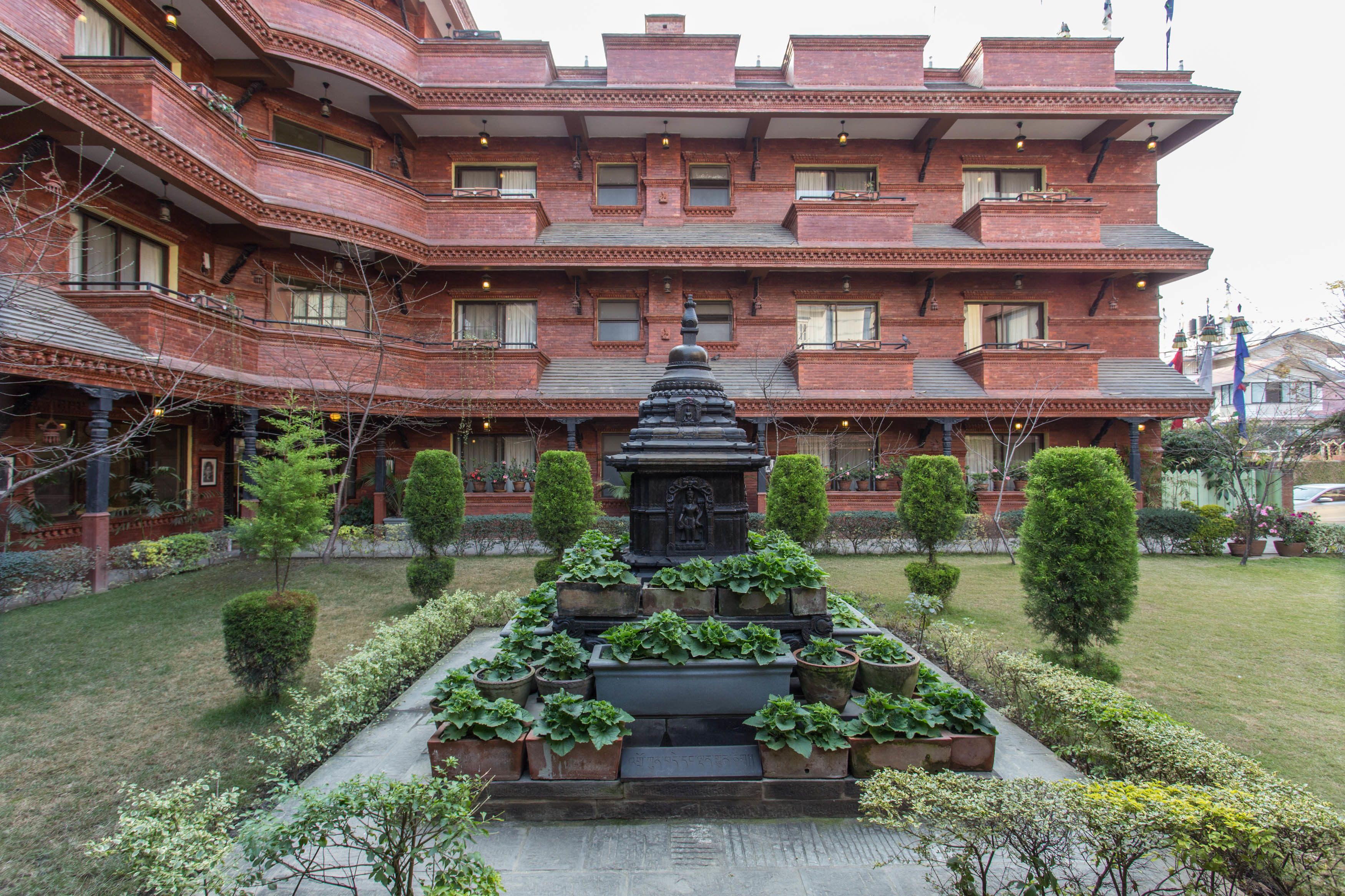 A large brick building with multiple balconies and a central garden with a statue.