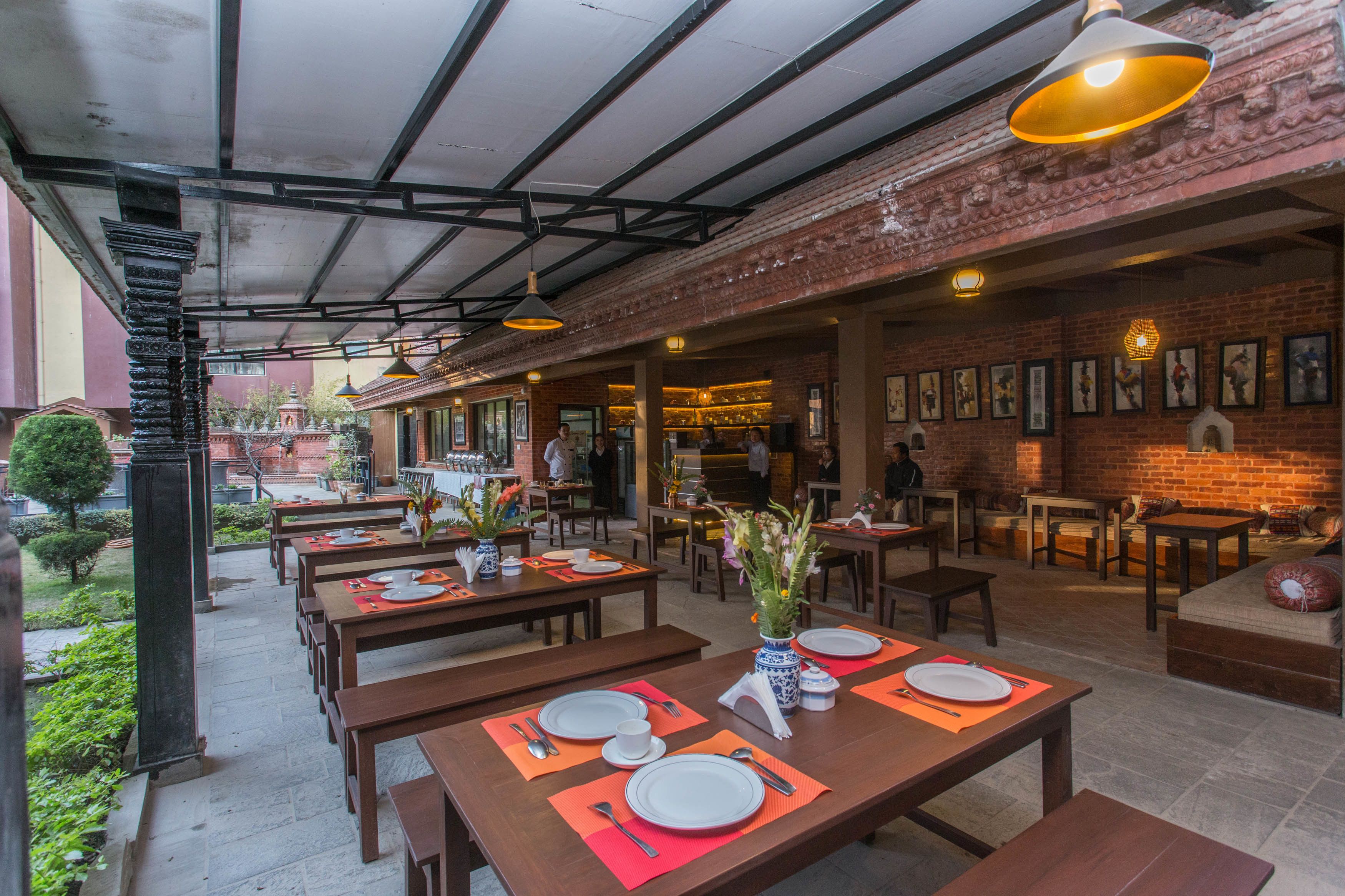 An outdoor dining area with wooden tables and benches, some with orange placemats.