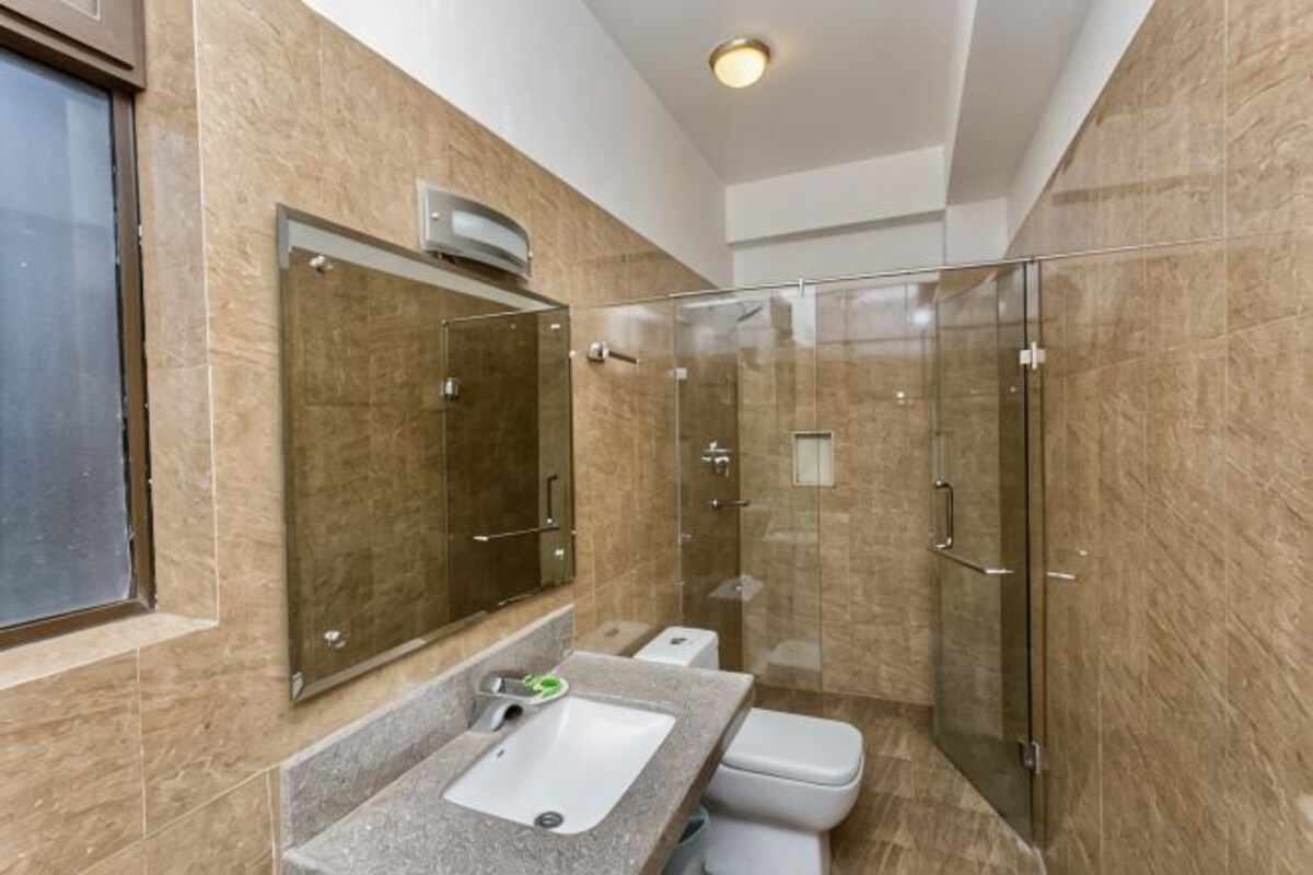 Un baño con cabina de ducha de vidrio, un lavabo y un inodoro.
