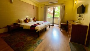 Een hotelkamer met een bed, een bureau, een stoel, een airconditioner en een televisie.