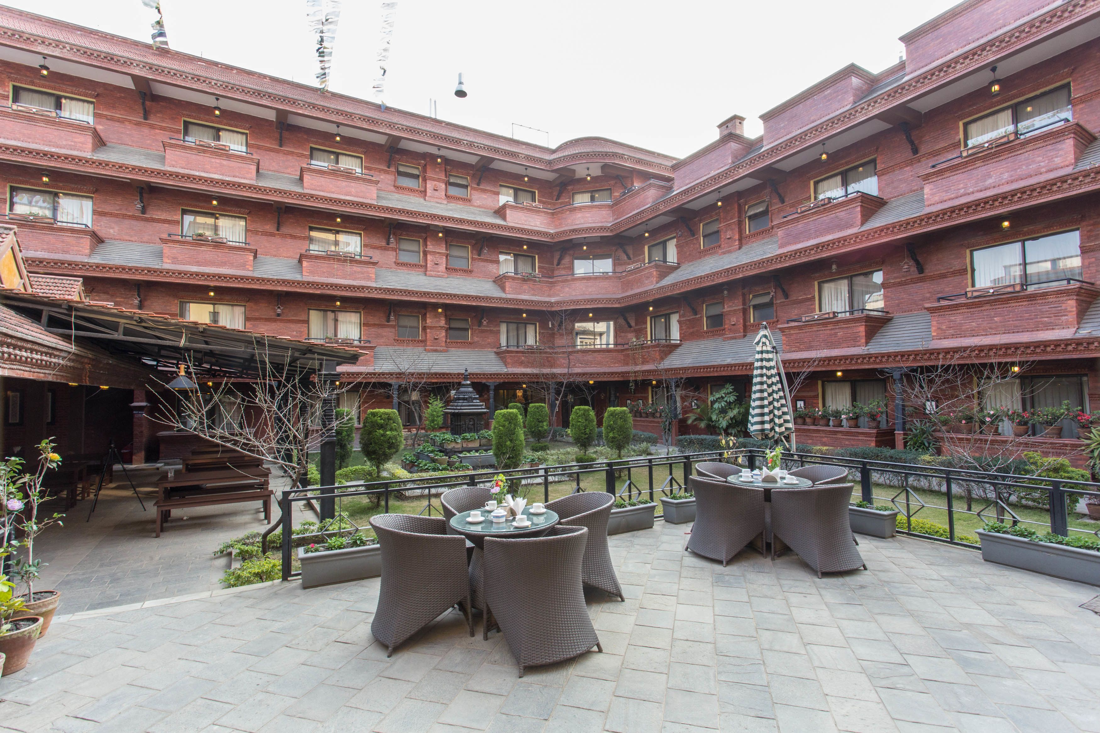 A courtyard with outdoor seating, a brick building, and potted plants.