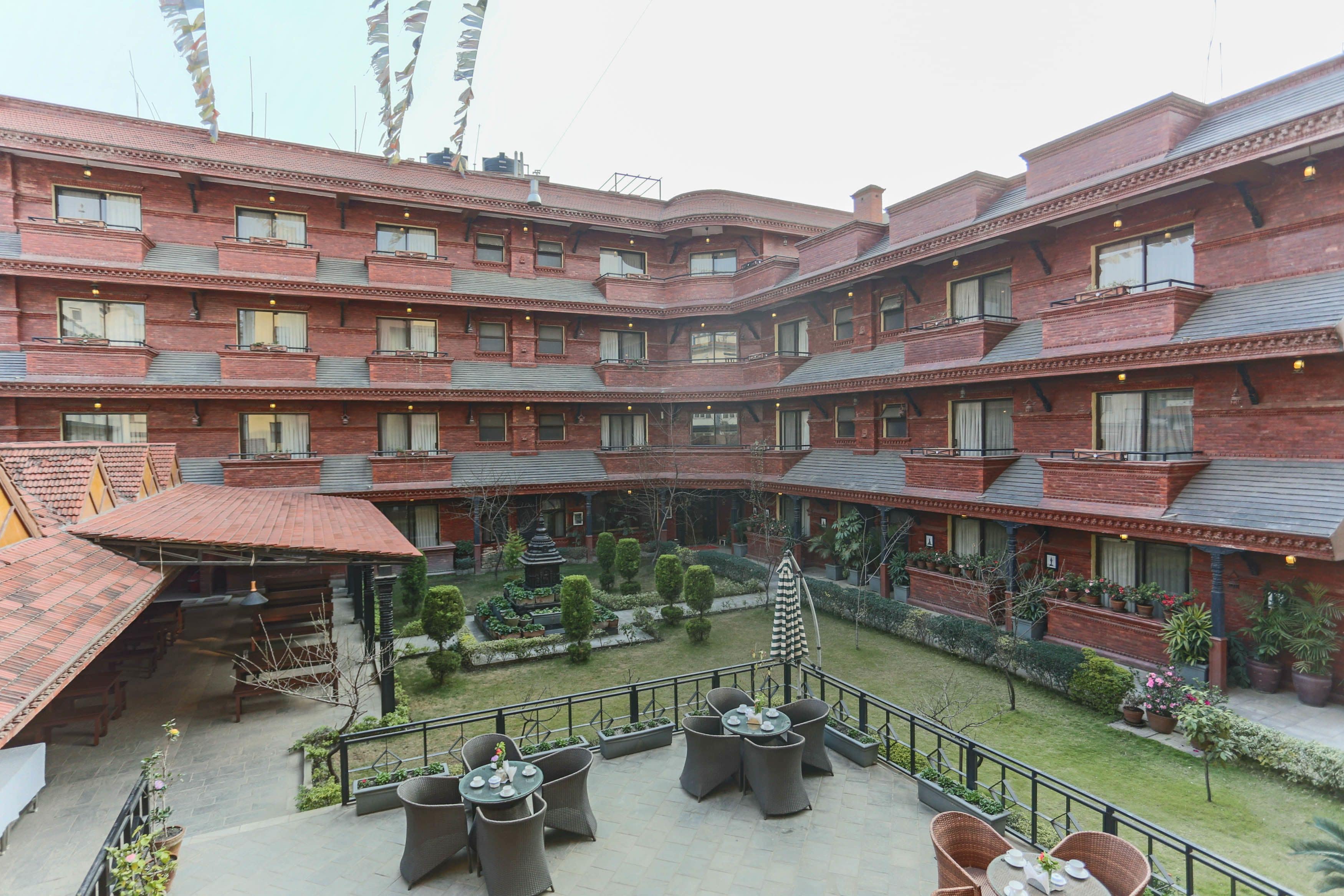 A multi-story hotel with a courtyard featuring outdoor seating and potted plants.