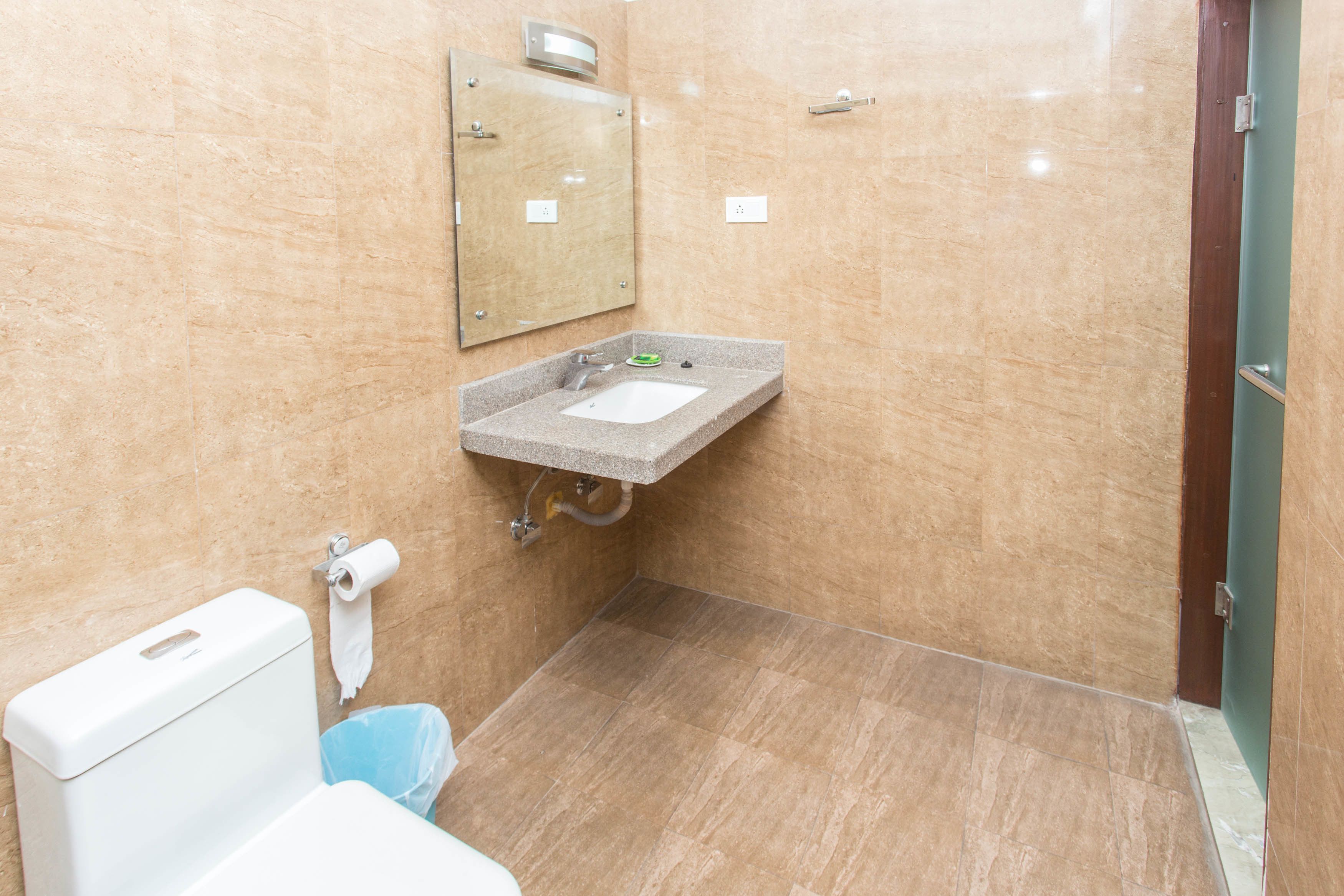 A bathroom with a toilet, sink, and mirror.